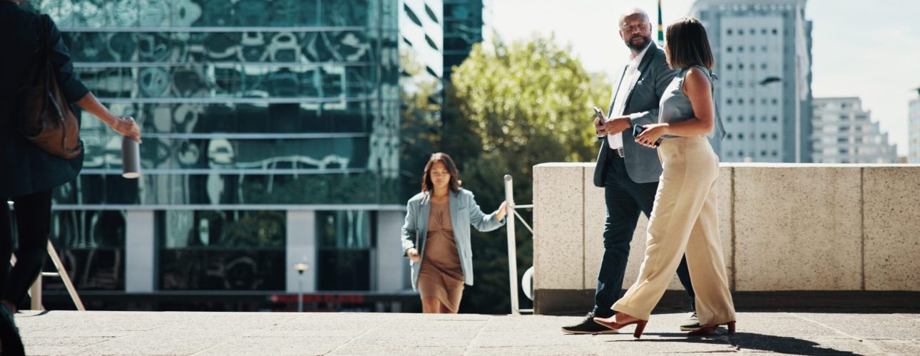 Business, employees and walking in town with conversation for project ideas, campaign planning or urban commute. Businessman, woman and corporate journey to appointment, meeting and career discussion.