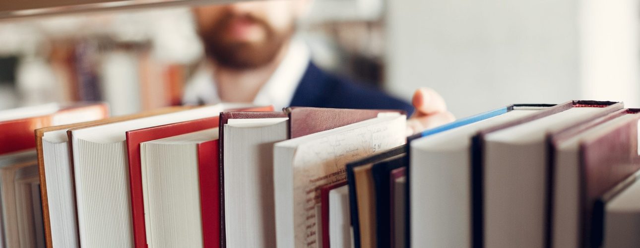 Man in a library. Guy in a black suit. Student with a books.